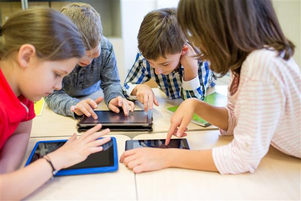 Elementary-aged students in a group using touchscreen tablets